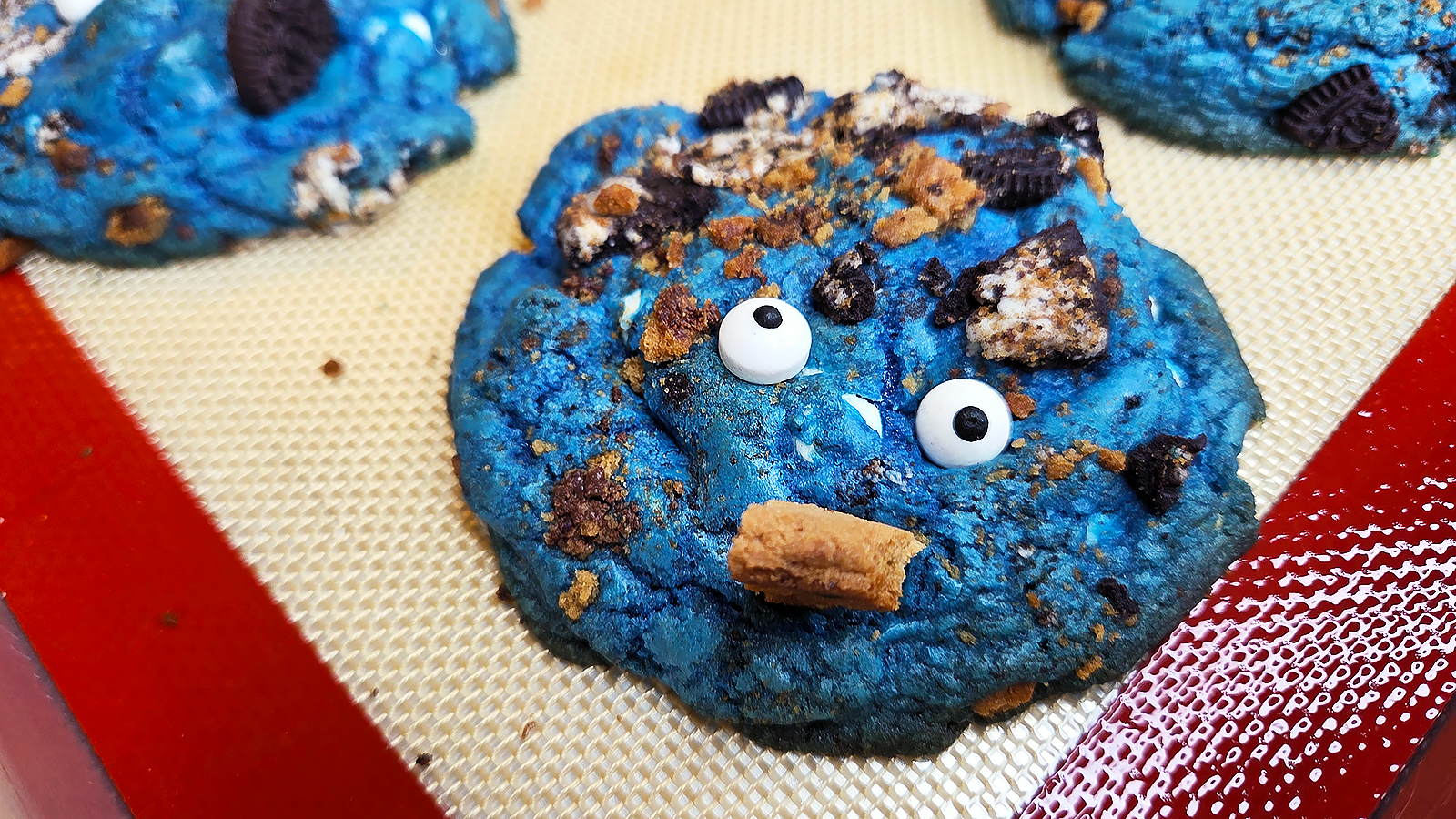 Bright blue Cookie Monster cookies loaded with Oreos and cookie pieces on a tray